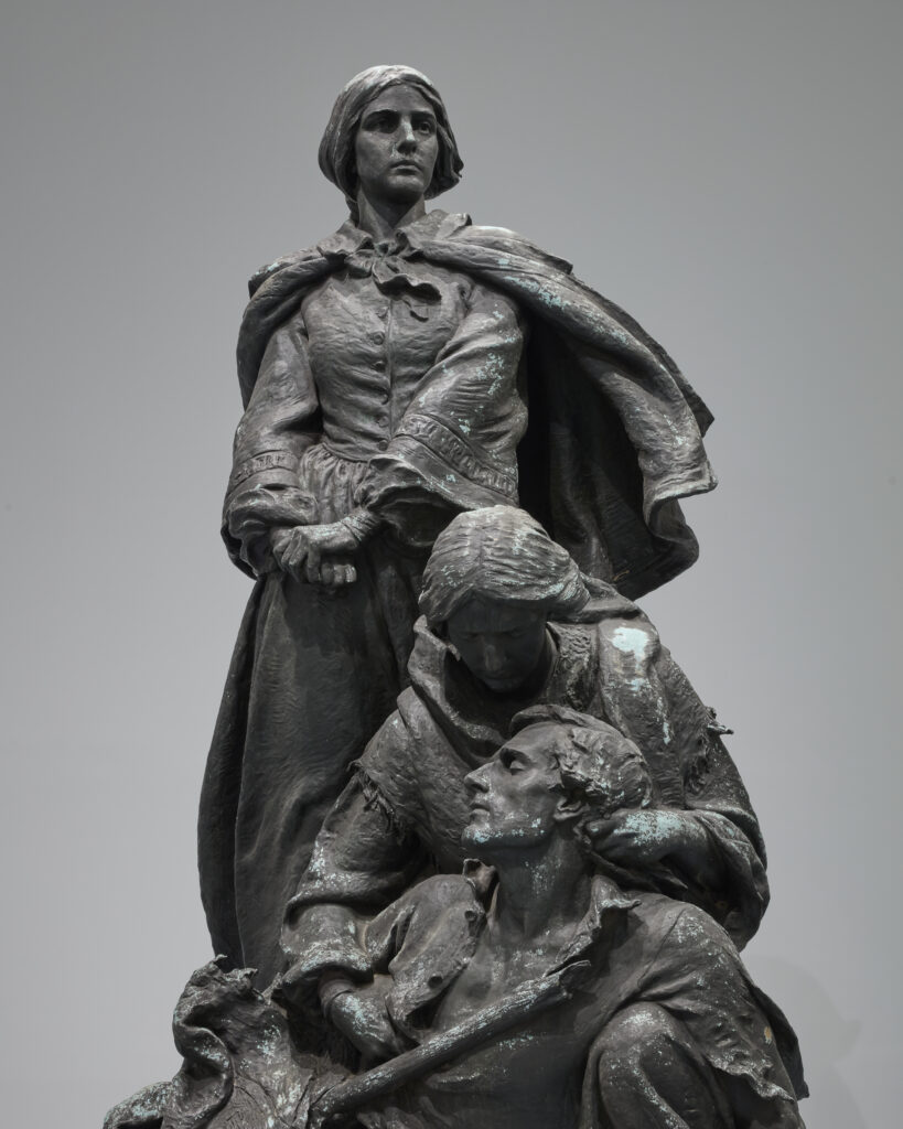 Bronze statue of a standing woman looking off into the distance. Below her, another woman holds a dying Confederate soldier