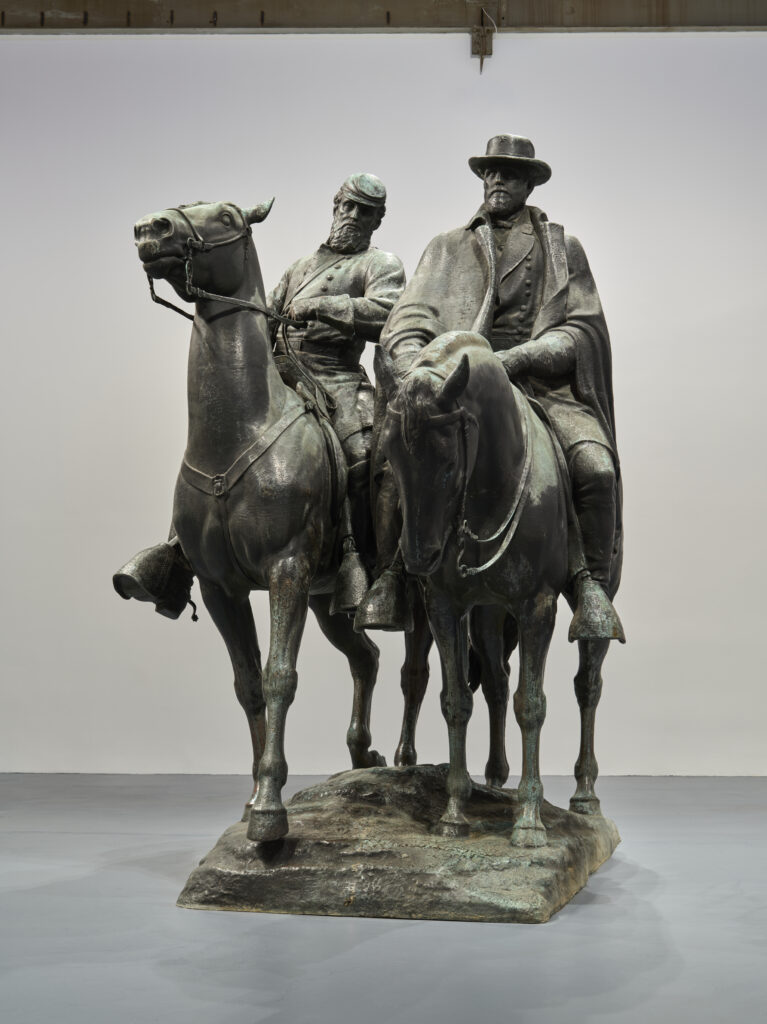 Bronze statue of Robert E. Lee & Stonewall Jackson on horseback. Jackson wears a Confederate uniform and kepi hat. Lee wears a Confederate uniform, overcoat, and brimmed hat.