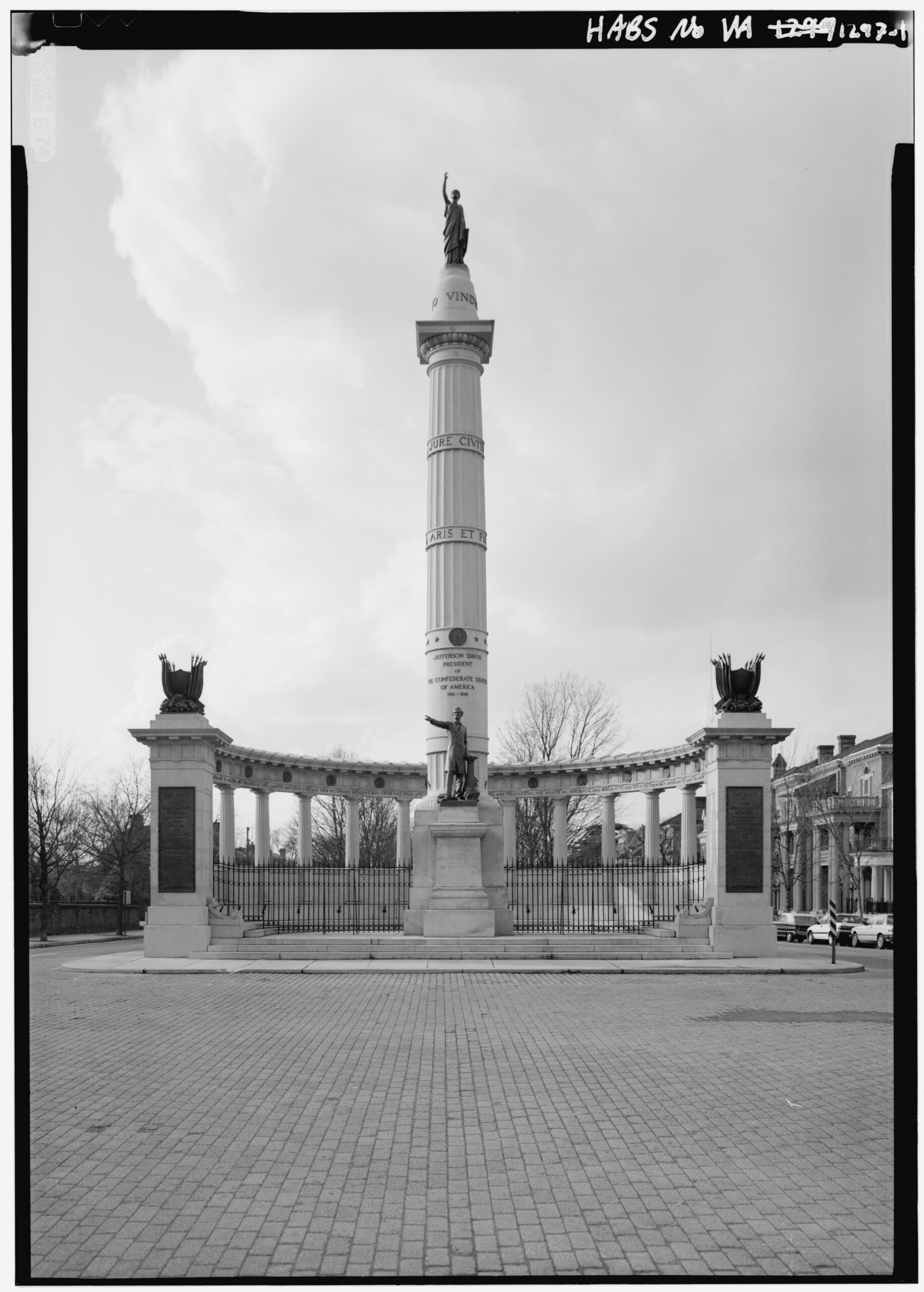 Black and white photo of elaborate granite colonnade and tall column. A statue of an allegorical figure sits atop the column while a bronze of Jefferson Davis sits at the base.